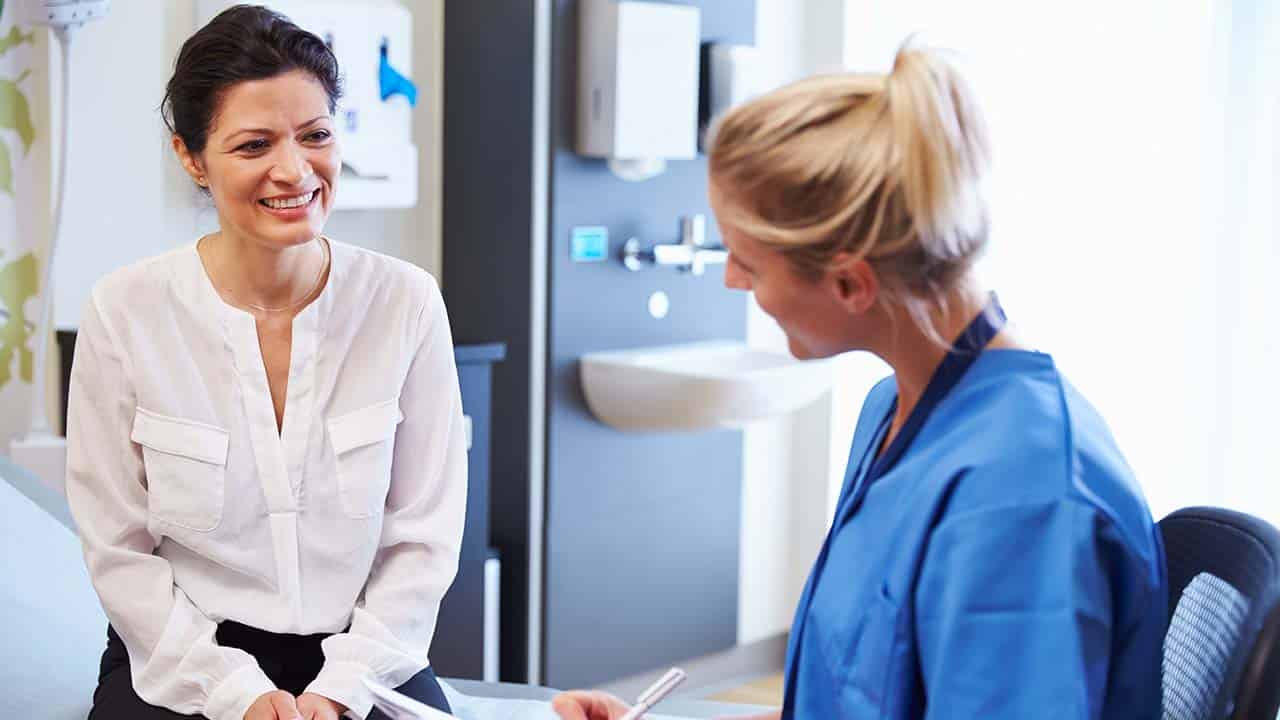 weight loss physician in palm beach gardens sits on the exam table talking with a patient about the program at the clinic